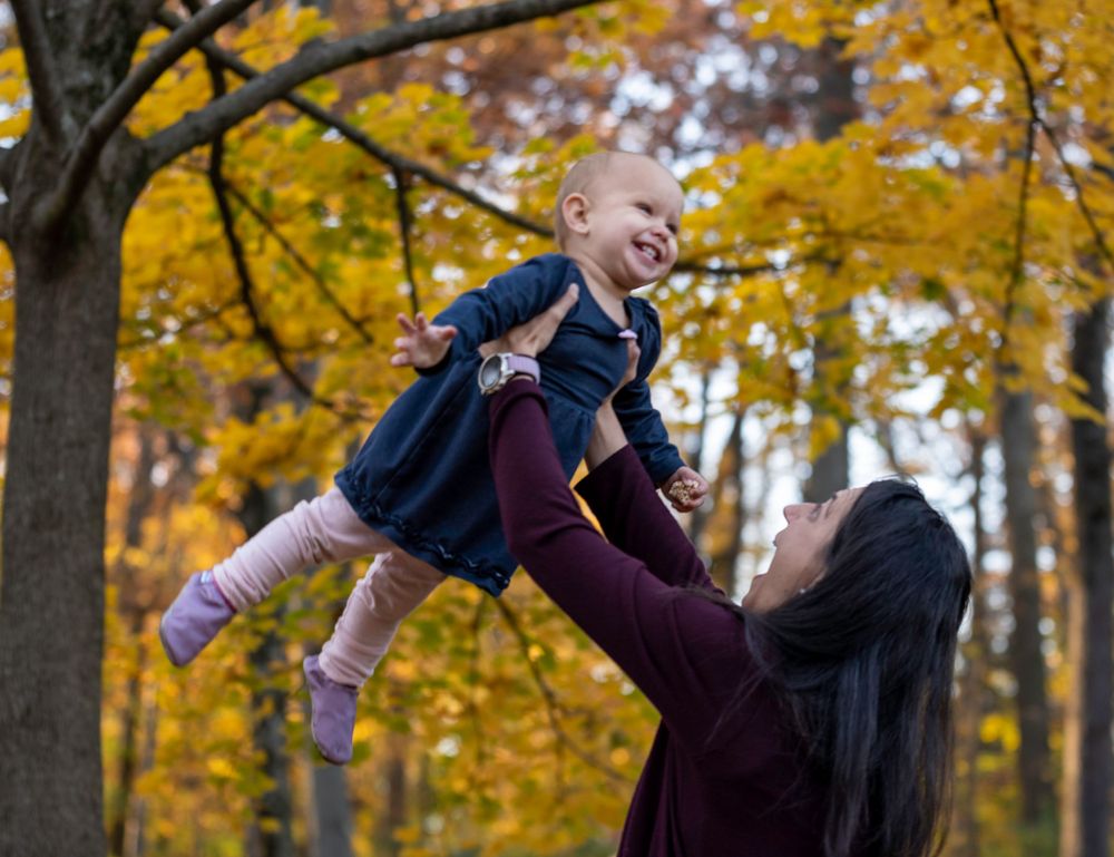 Candid autumn family photography showing joyful interaction against golden fall foliage.