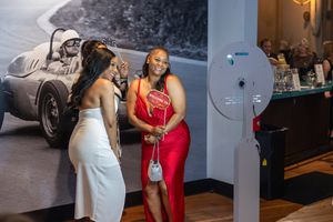 Event attendees posing for a photo near the silent auction display at a non-profit charity gala