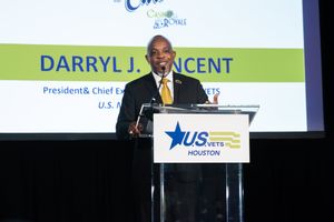 Keynote presenter on stage at a nonprofit fundraising gala inside a luxury Houston event venue