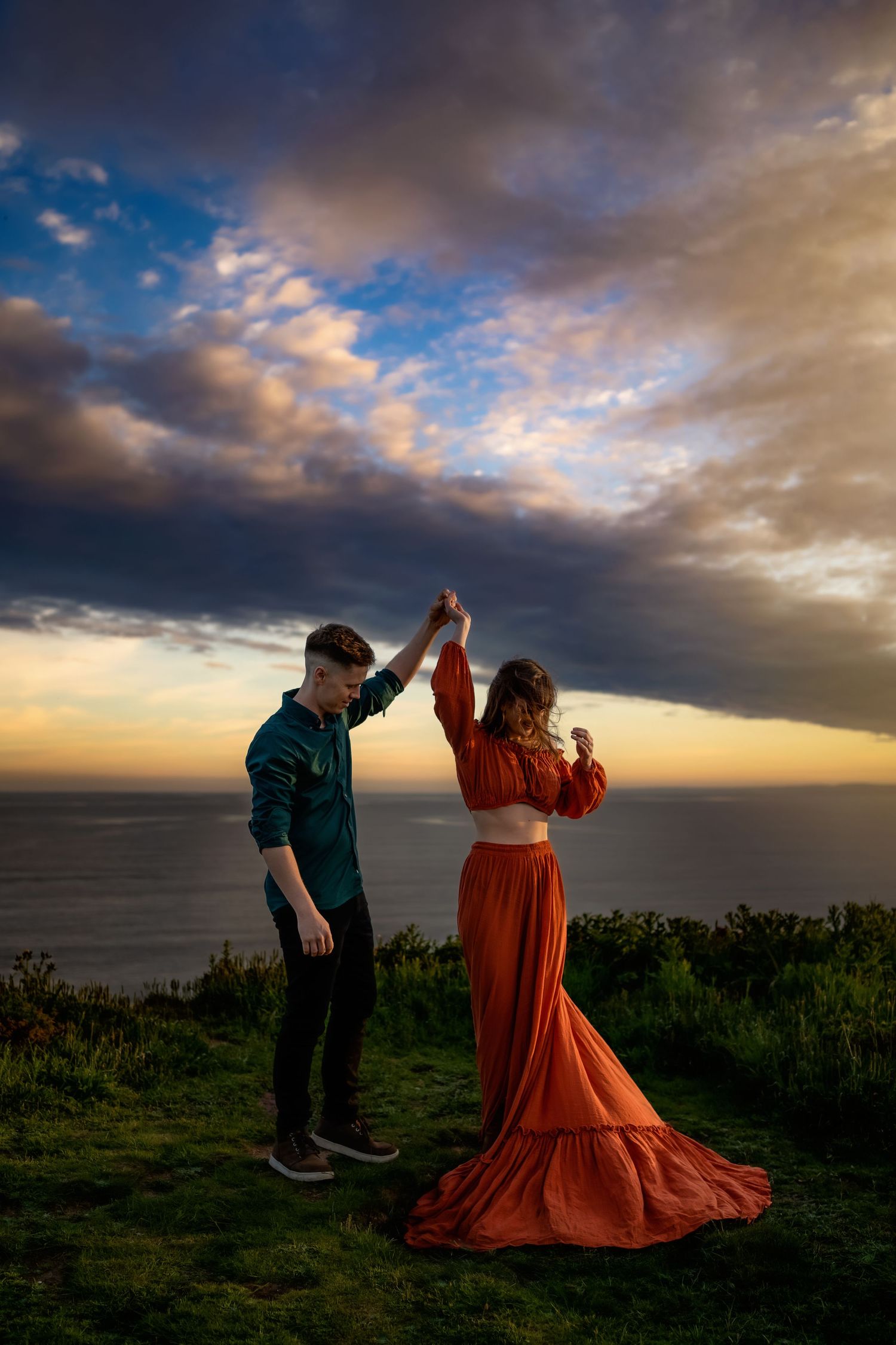 Barton on Sea engagement photoshoot. A couple dancing on the cliff with a stunning sunset sky in the background.