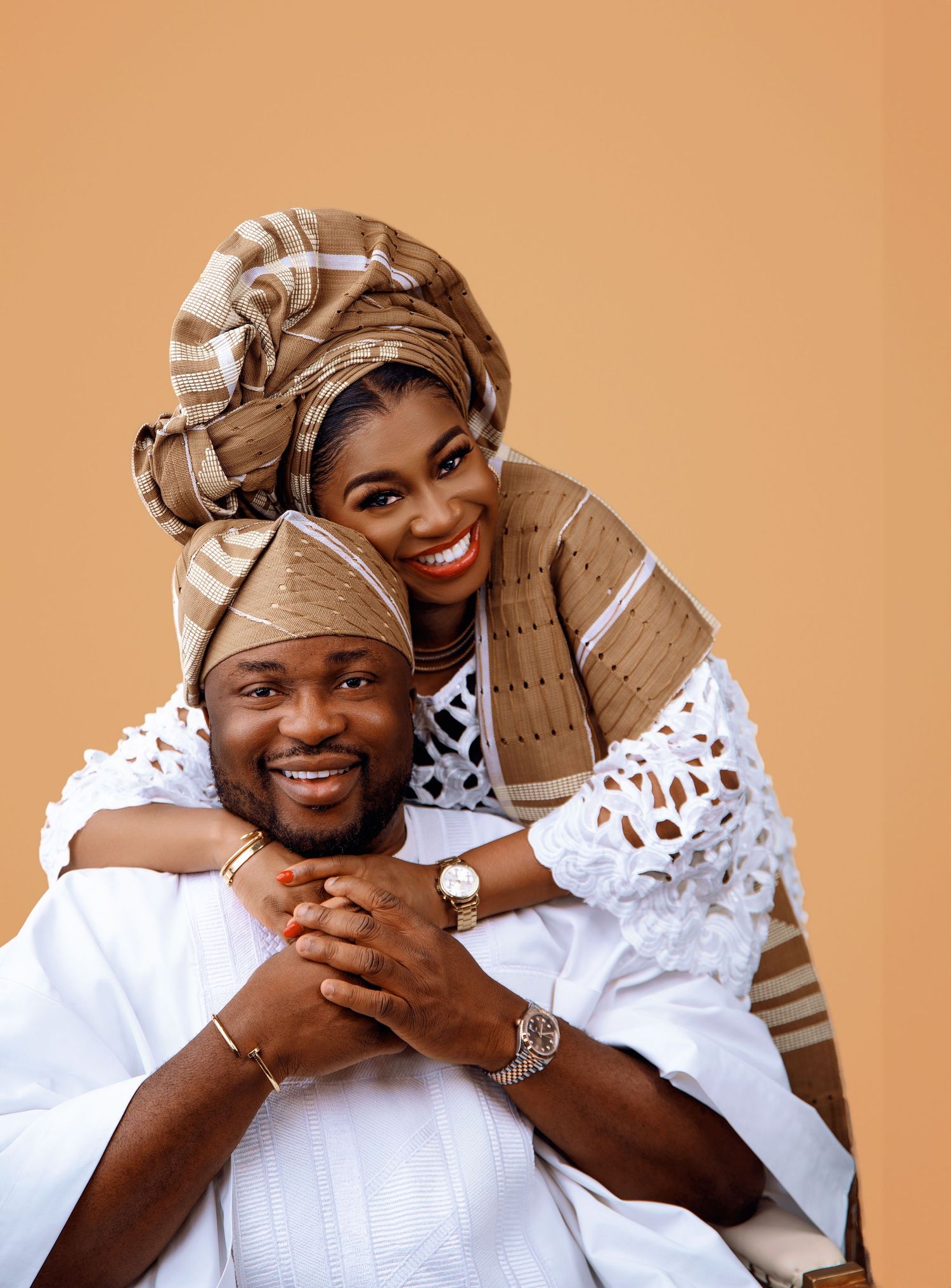 Traditional cultural portrait in white and beige traditional attire against orange background.