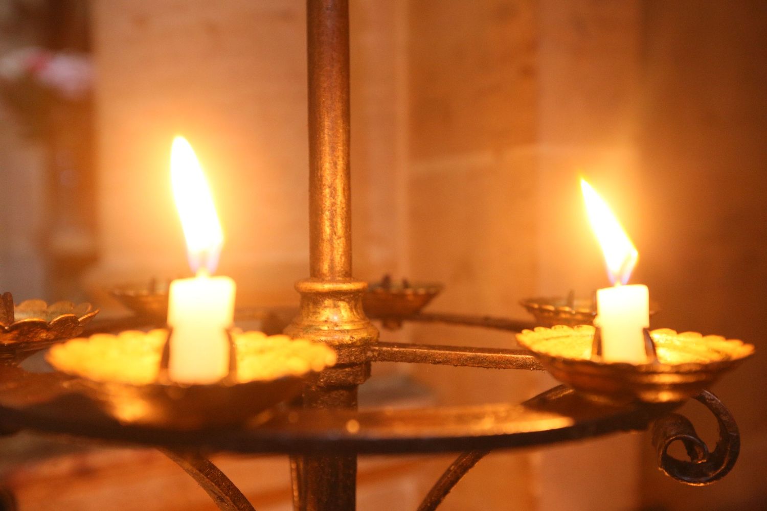 Row of glowing candle flames creating warm atmospheric lighting in dark setting.
