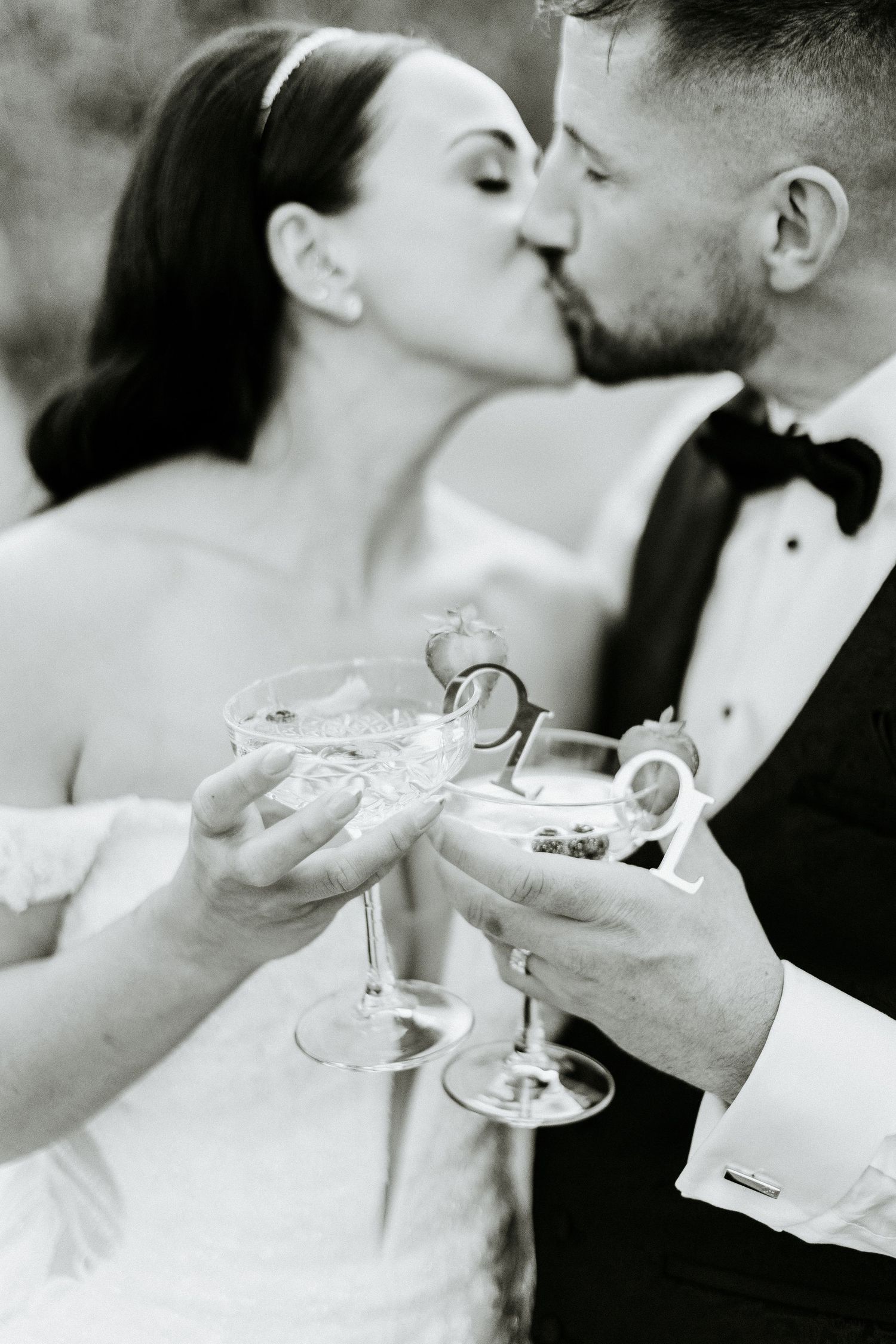 Black and white photo of newlyweds sharing champagne toast and intimate moment.