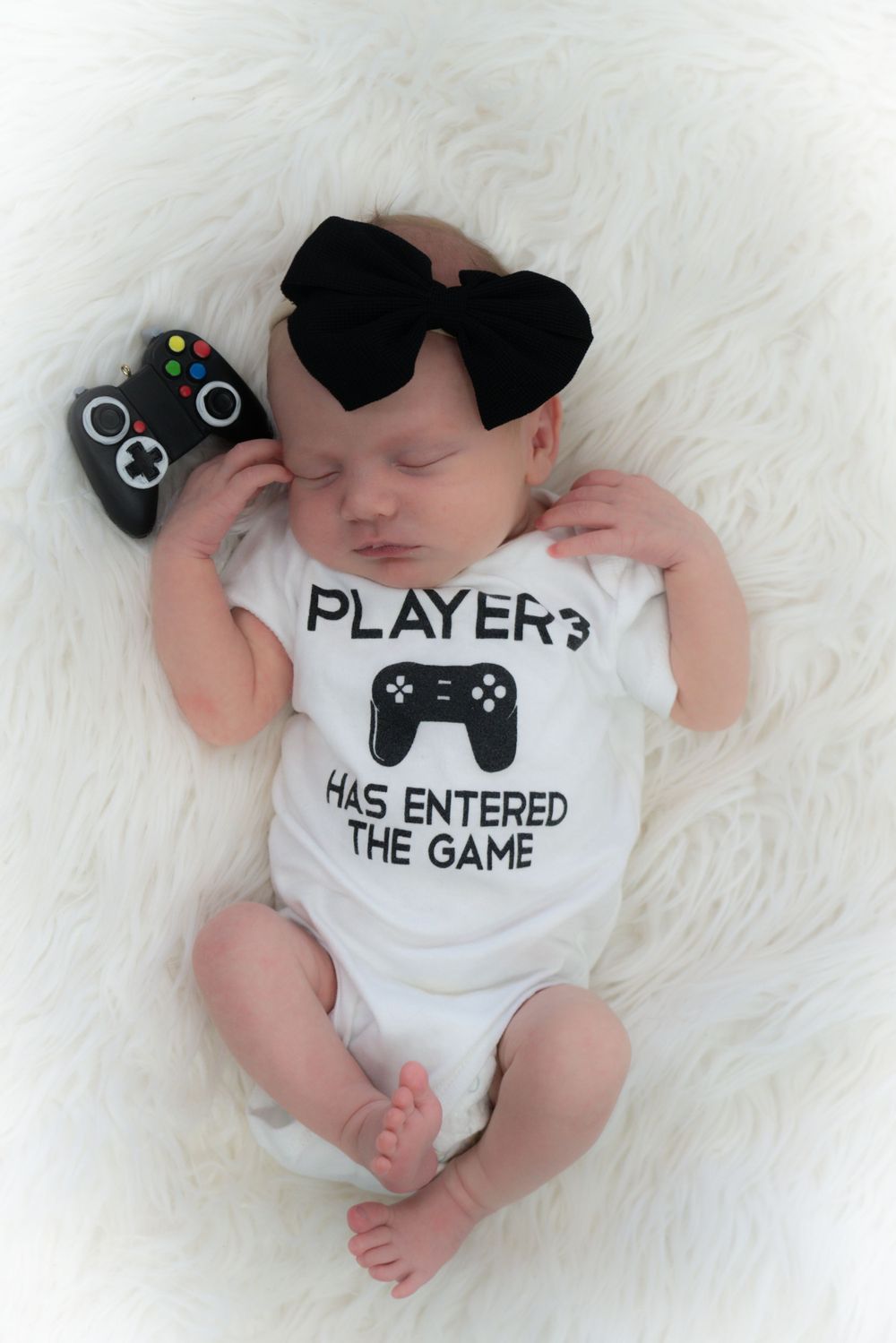 Gaming-themed newborn photo with controller onesie, sunglasses, and Xbox controller prop.