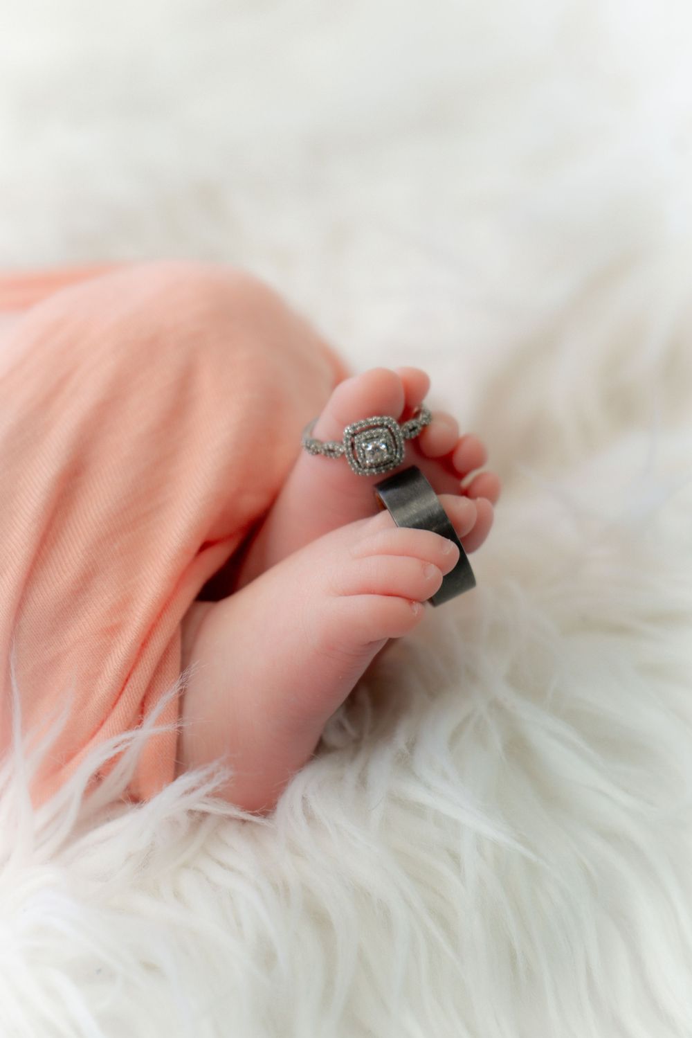 A delicate vintage-style ring with intricate detailing rests on soft white fur texture, photographed in dreamy lighting.