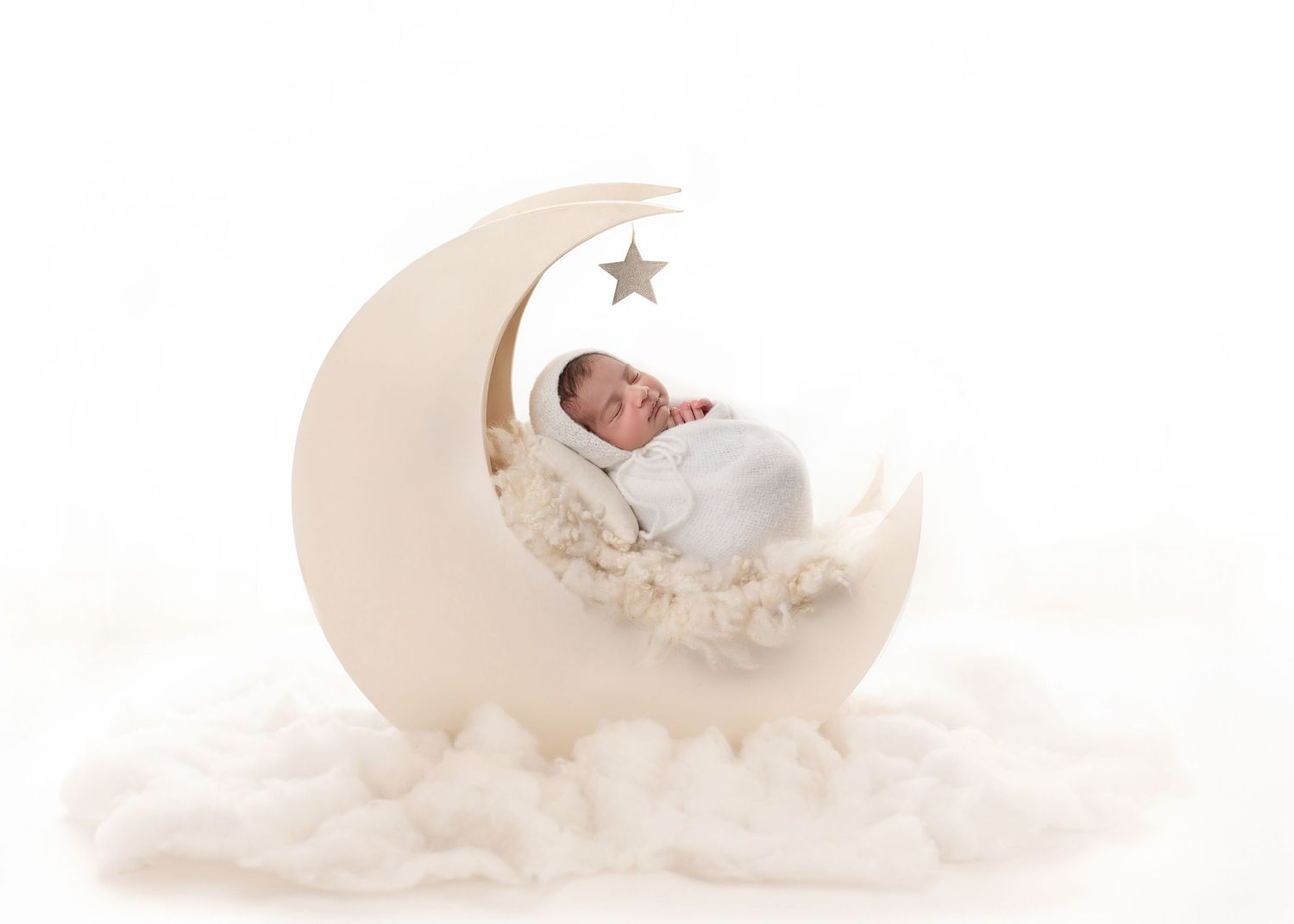 Dreamy newborn photos with baby sleeping on crescent moon prop against white background.