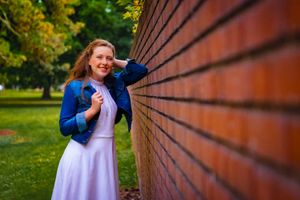 young woman poses against a brick wall