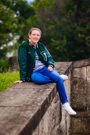 young woman sits in stone wall