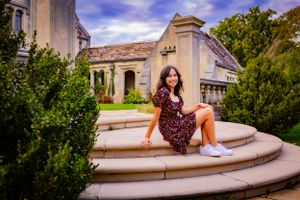 High school senior posing confidently outdoors with a natural smile, dressed in stylish attire, with soft golden sunlight highlighting their