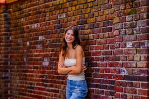 senior girl leans against brick wall