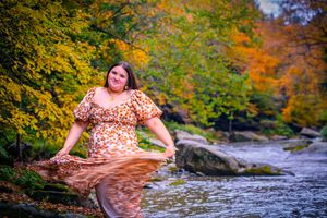 girl twirls her dress colorful trees and flowing river behind her