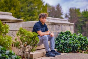 High school senior posing confidently outdoors with a natural smile, dressed in stylish attire, with soft golden sunlight highlighting their