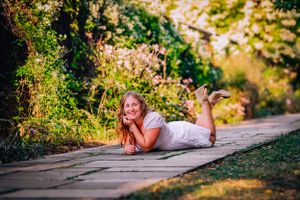 High school senior posing confidently outdoors with a natural smile, dressed in stylish attire, with soft golden sunlight highlighting their