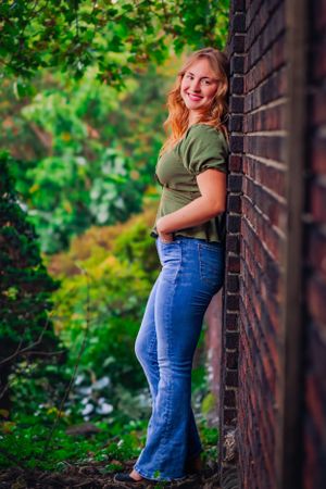 High school senior posing confidently outdoors with a natural smile, dressed in stylish attire, with soft golden sunlight highlighting their
