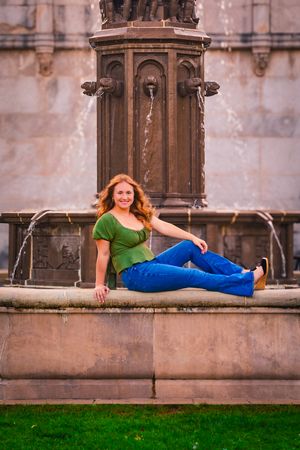 High school senior posing confidently outdoors with a natural smile, dressed in stylish attire, with soft golden sunlight highlighting their