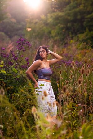 in a field of tall flowers with the sun setting behind her this senior pictures tells a story