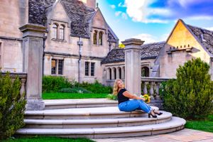 a wide angle picture of a senior girl posed on the steps of a mansion