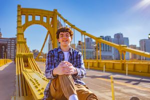 High school senior posing confidently outdoors with a natural smile, dressed in stylish attire, with soft golden sunlight highlighting their