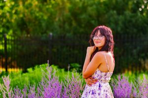 Lady wearing floral dress surrounded by lavender flowers in a picturesque field.