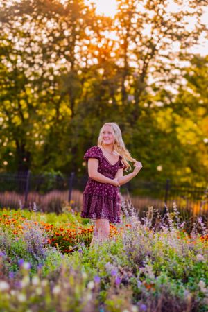 senior girl poses with golden light in a garden