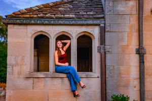 a girl sits in archway openings, perfectly posed for a senior session