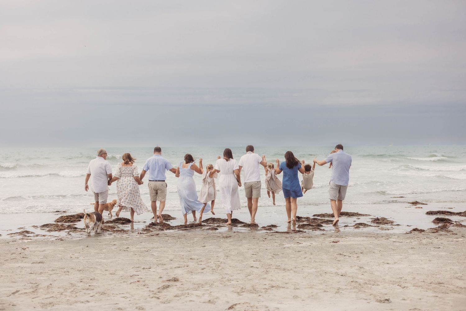 Group playing and running together on sandy beach during golden hour.