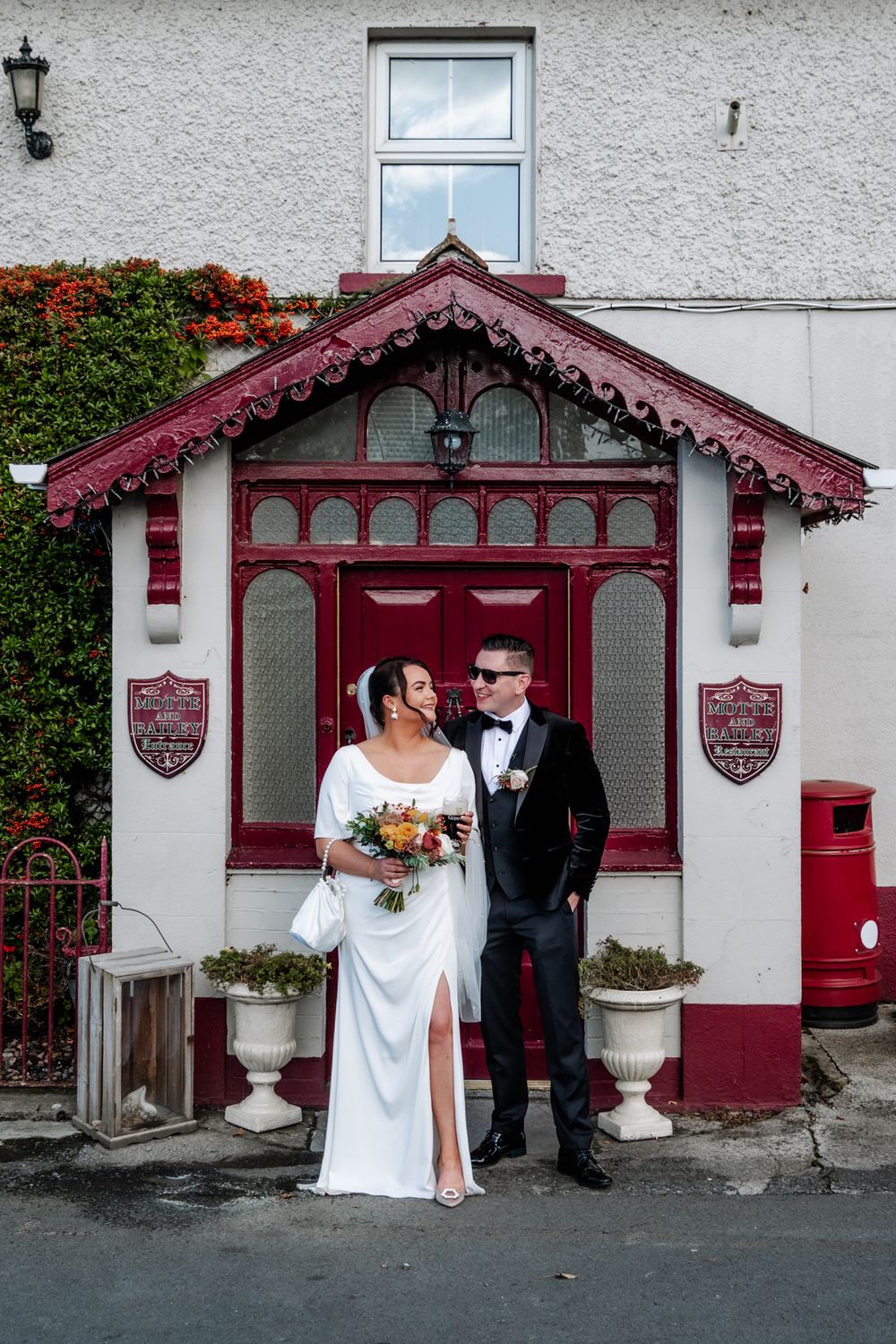 Bride and groom posing in front of the red entrance of Motte and Bailey in Athlone, Ireland after their wedding ceremony.
