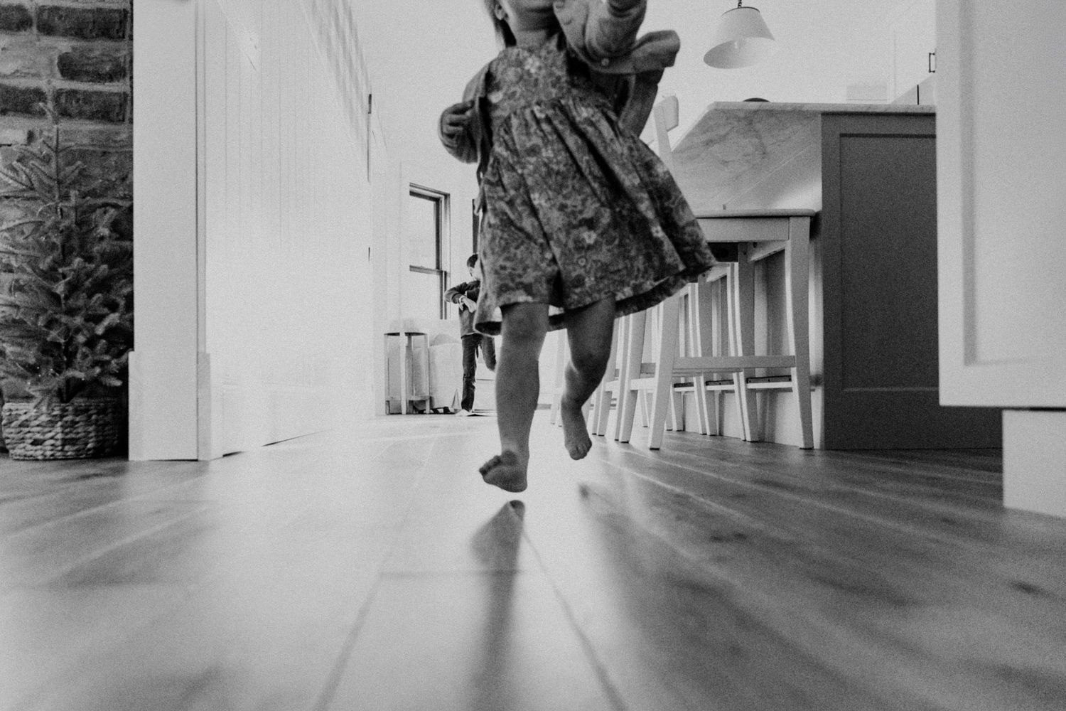 Documentary family photo of a toddler girl running through the kitchen in their Minneapolis home