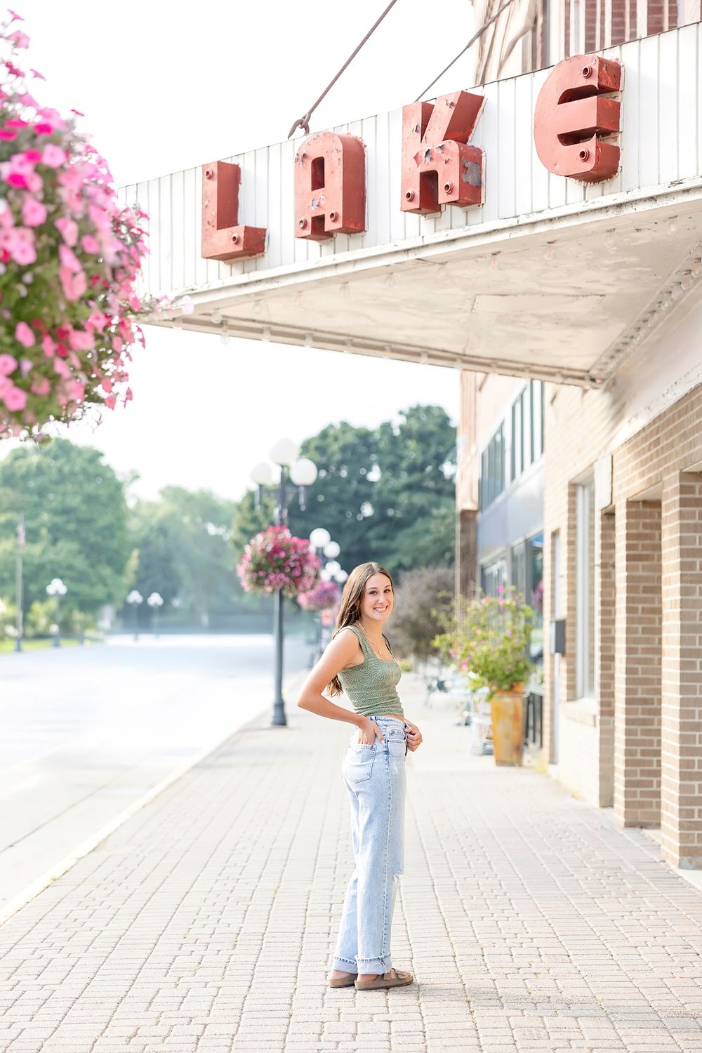 Lake view walkway with pink flowers and white columns creating an elegant outdoor setting.