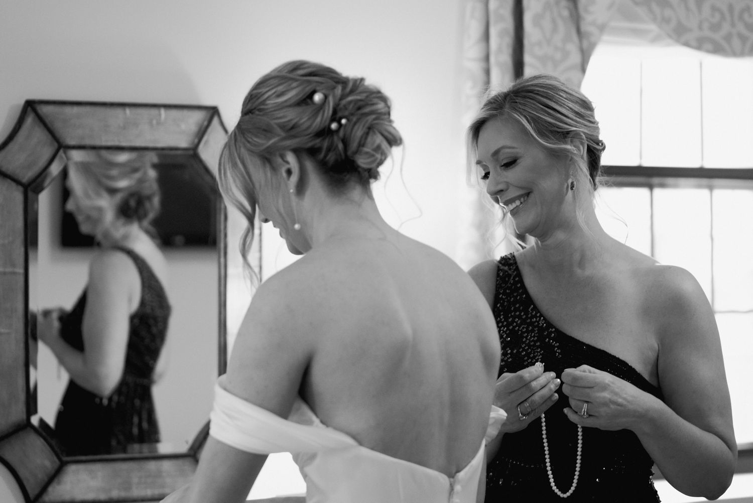 Black and white candid moment of wedding dress preparations.