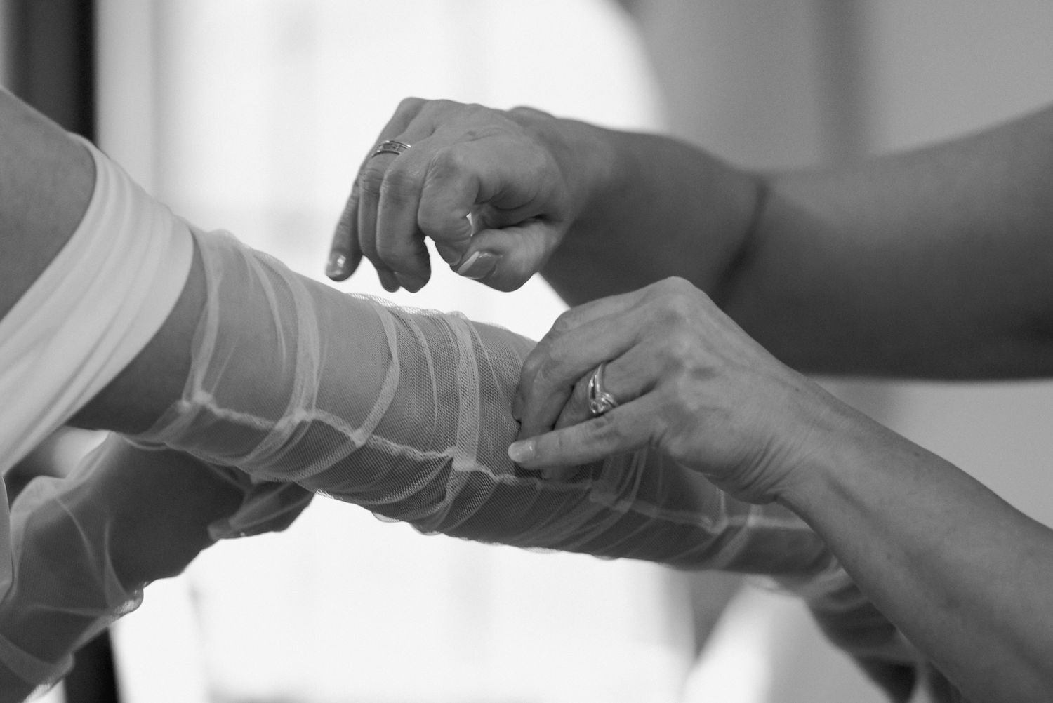 Black and white detail shot of hands adjusting bridal gloves.