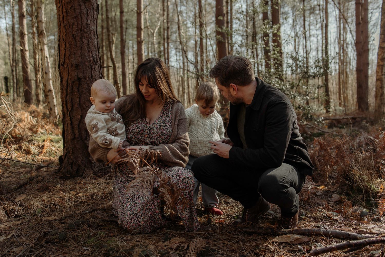 A family of four playing in the woods during a family photoshoot in Hampshire.