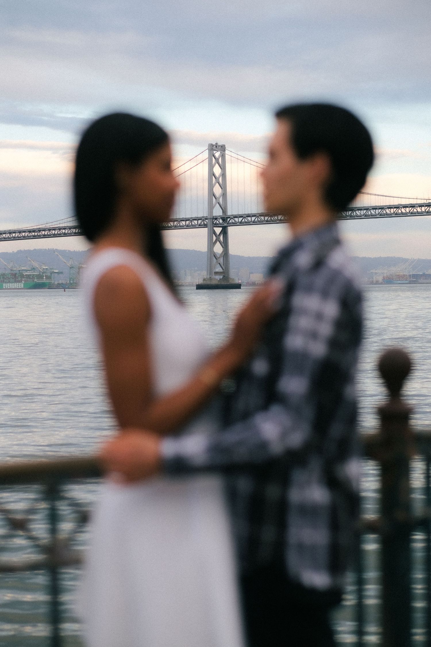 Couple in silhouette with San Francisco Bay Bridge in background during sunset.