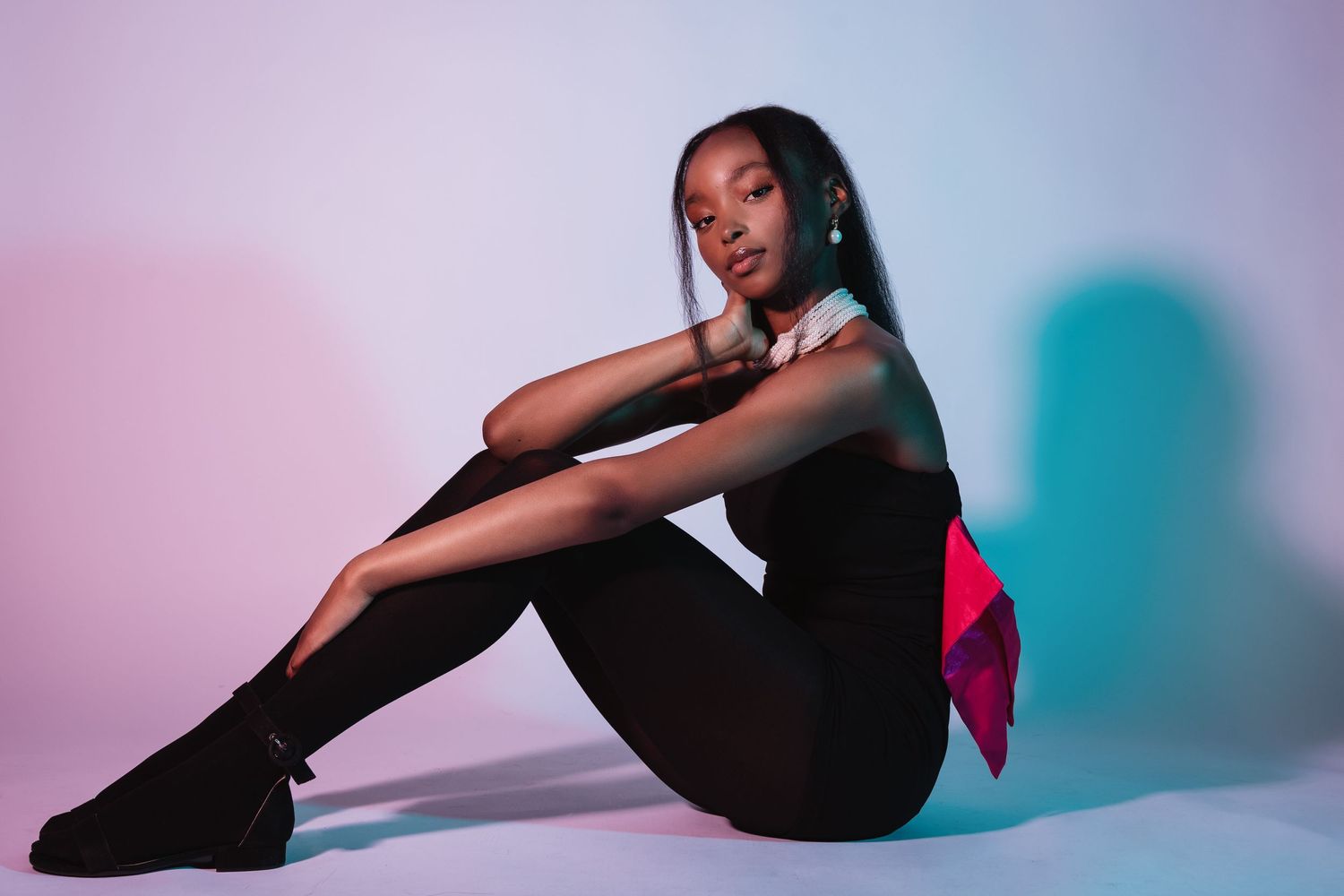 Artistic portrait with model against pink and blue gradient background.
