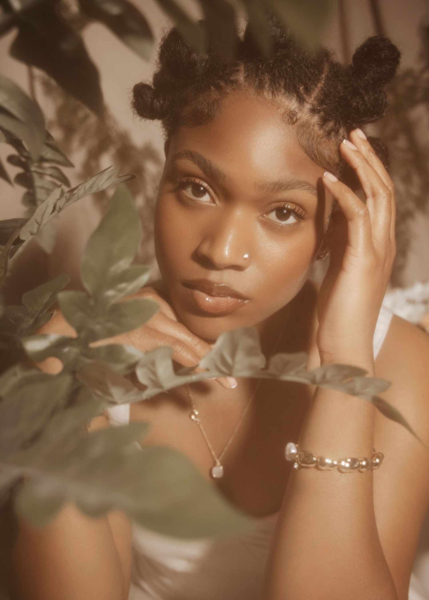 Dreamy portrait of a woman with natural hair surrounded by soft foliage.