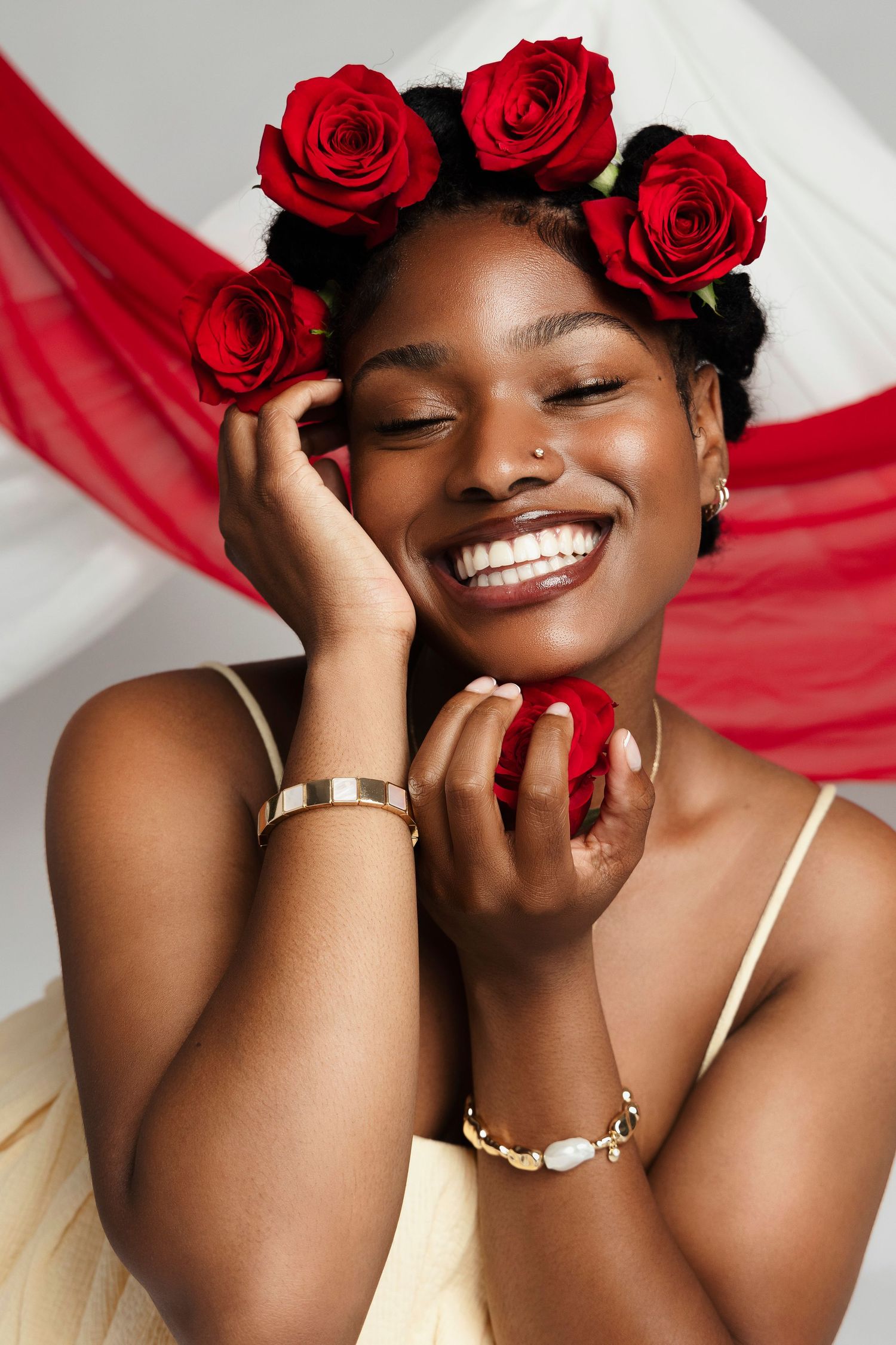 Romantic beauty shot with red roses in hair and flowing red fabric.