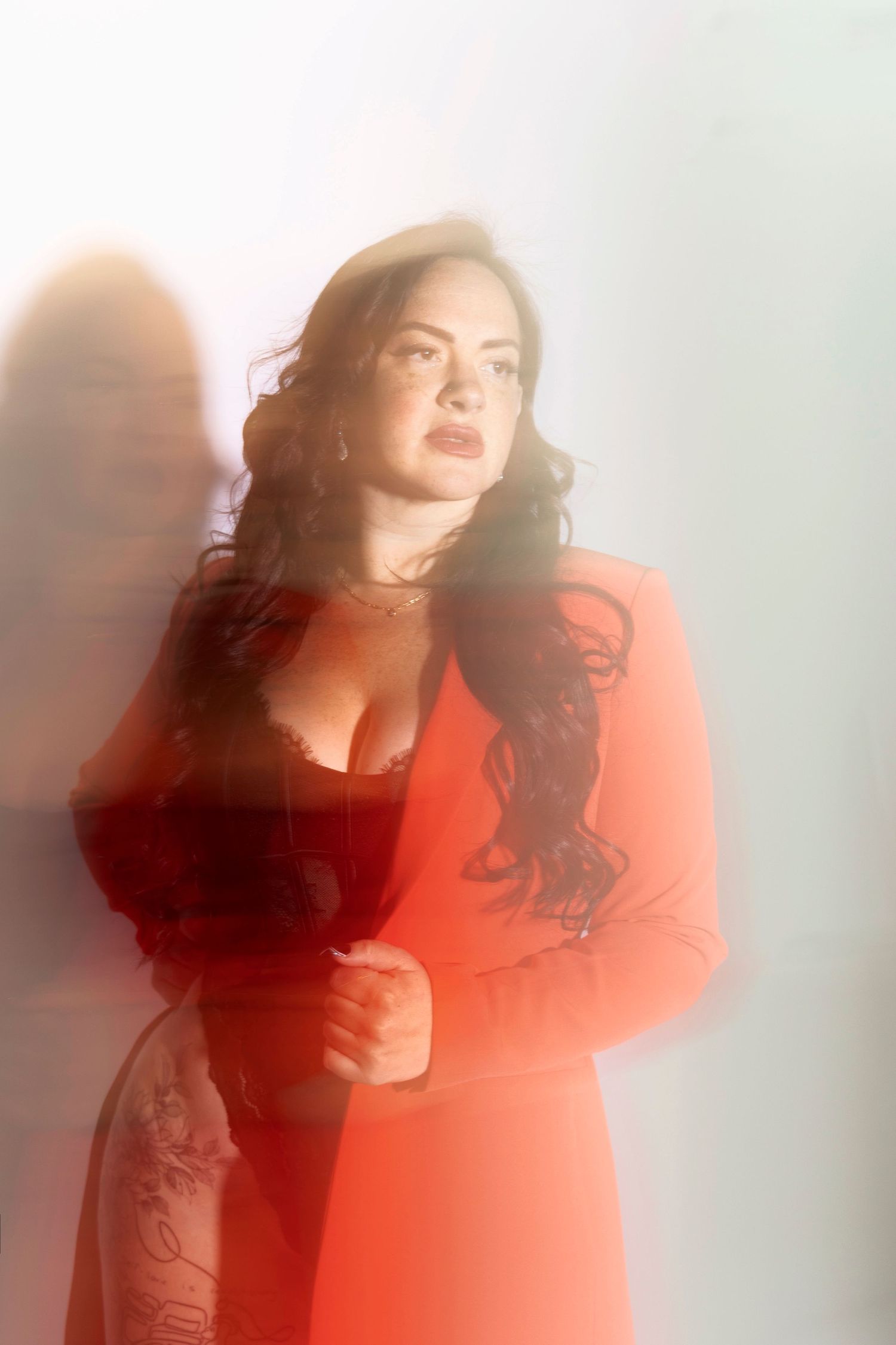 Artistic portrait in red dress with soft shadows against light background.