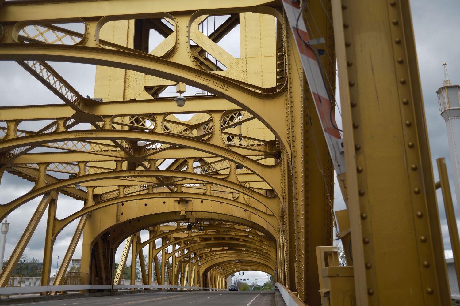 Yellow steel bridge interior with arched support beams and industrial architecture.