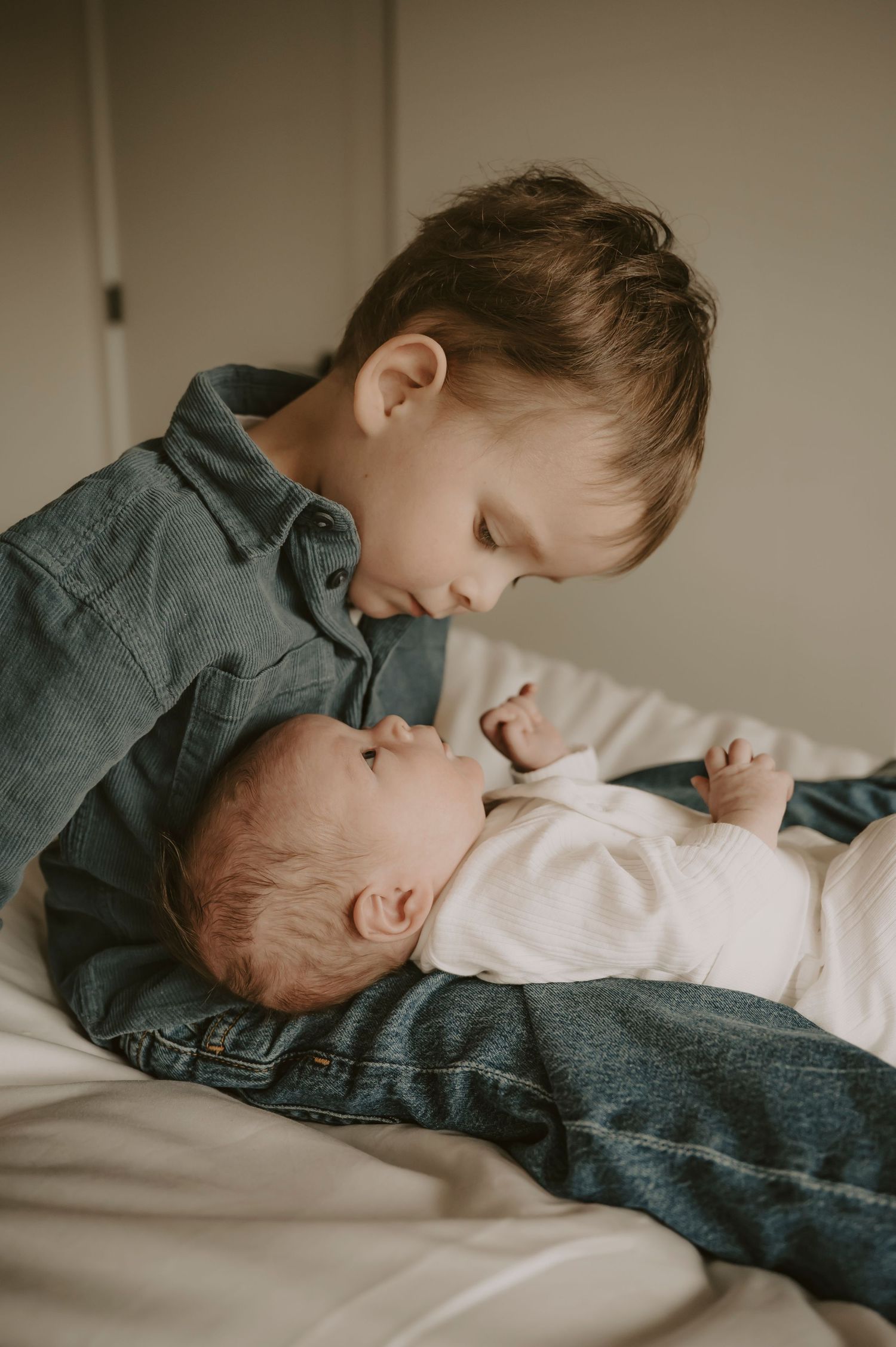 Intimate family moment captured in soft lighting against neutral background.