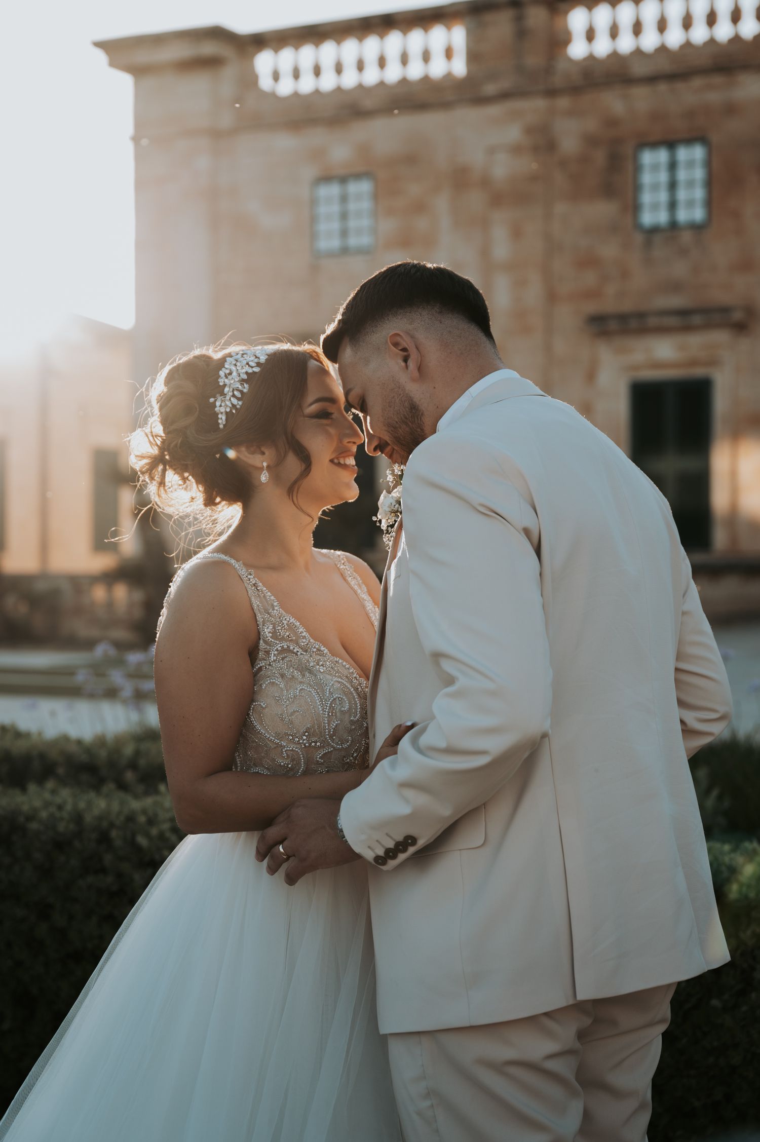 Romantic sunset wedding portraits against a historic stone building backdrop.