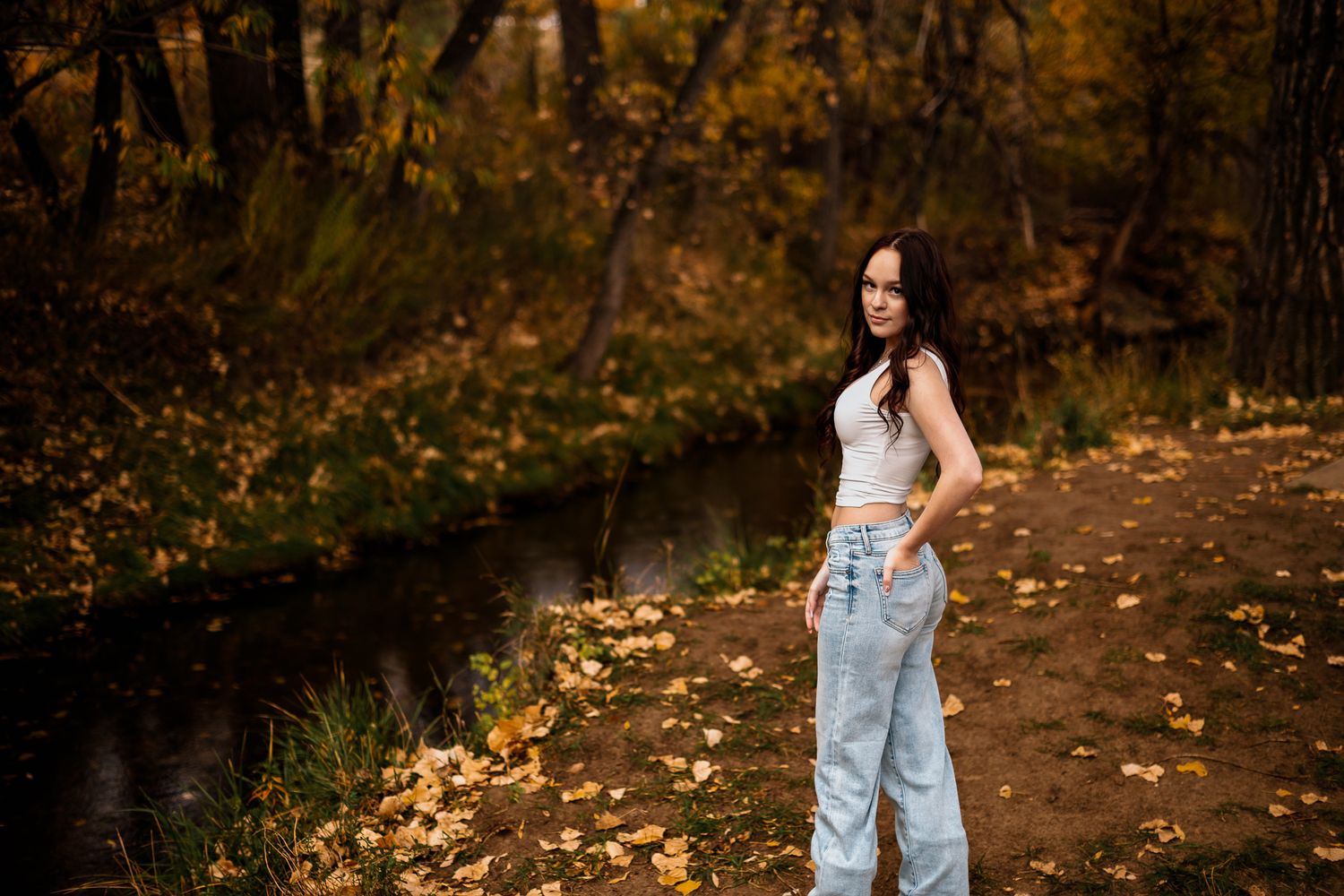 high school senior girl looking over her shoulder in front of a Littleton, CO creek