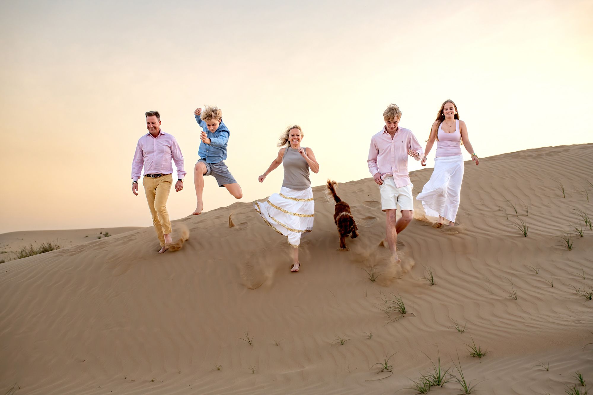 family running down dunes in desert