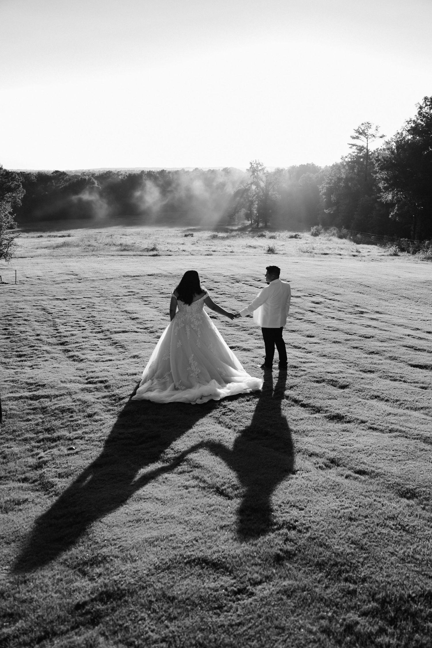 married couple looking at each other in an open field, sunlight lighting up the fog
