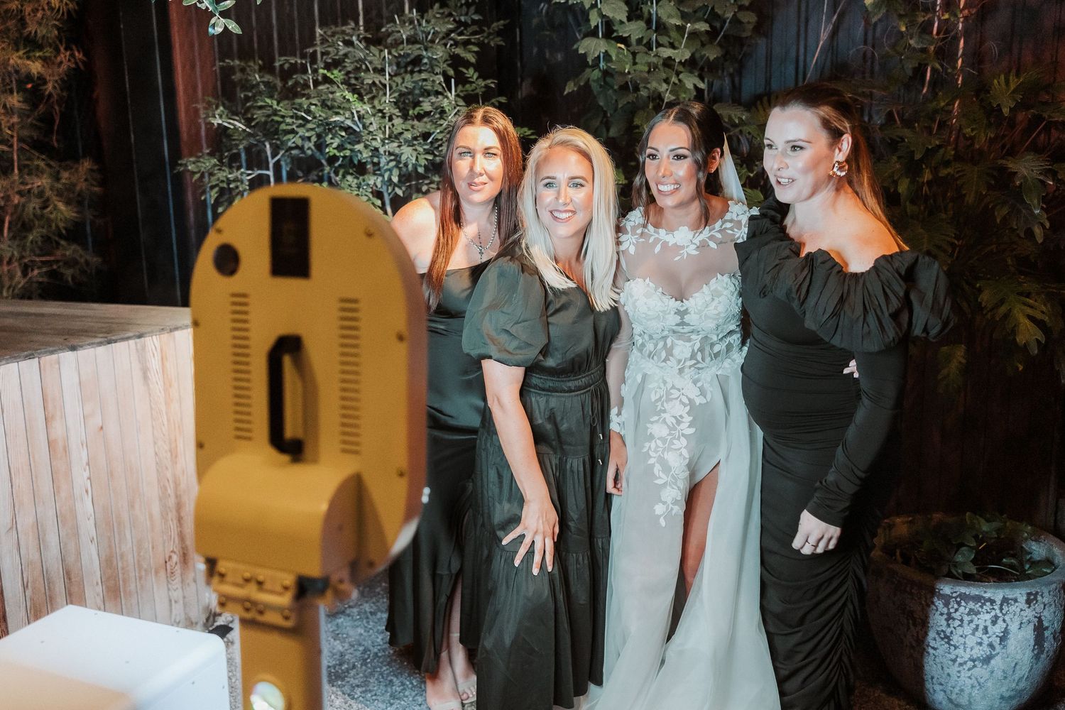 A group of wedding guests and wedding party members pose together during an evening celebration.