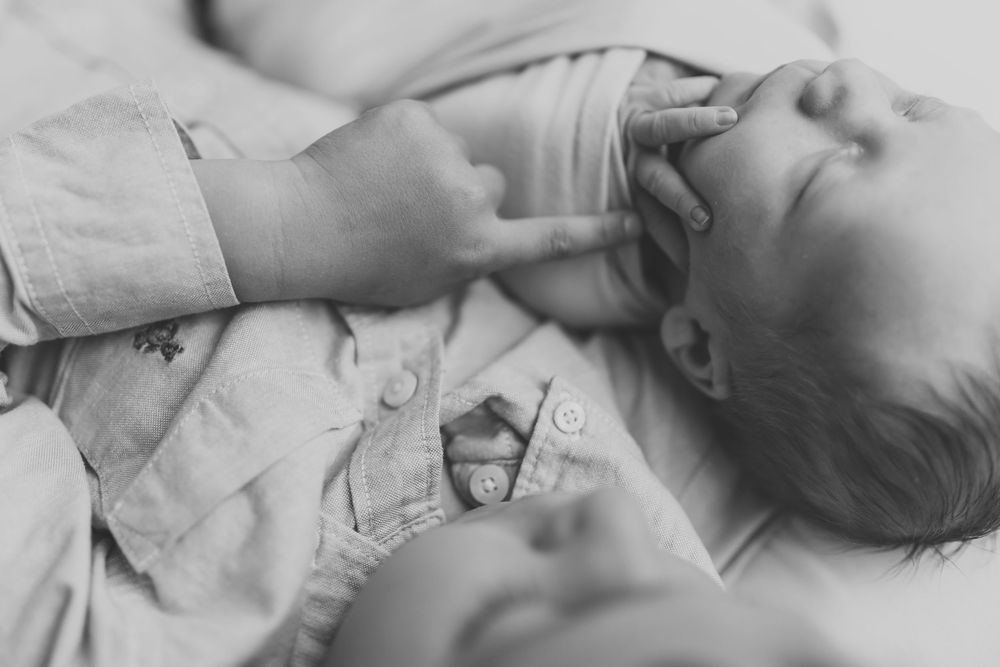 Black and white photo of two babies lying together, one gently touching the other's face.