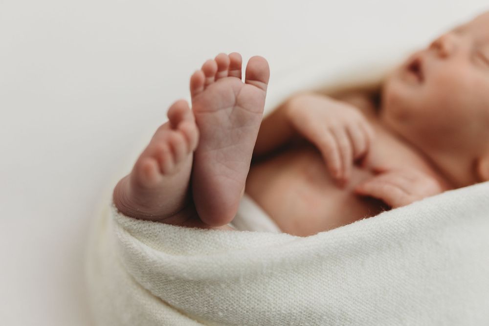 Close-up of newborn baby feet wrapped in a soft white blanket, perfect newborn photography.