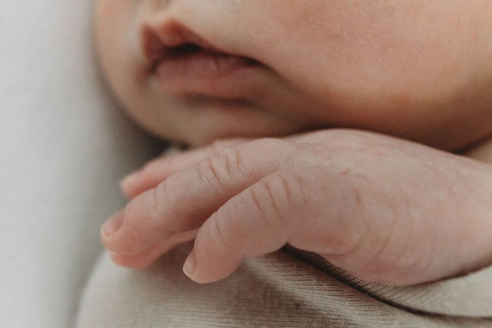 Close-up of a sleeping newborn baby's tiny fingers and lips, capturing delicate skin details.
