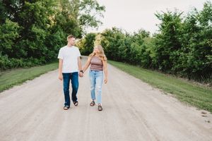 A casual couple walking hand in hand down a peaceful country road.