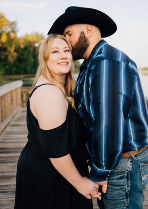 A loving couple embraces on a wooden bridge while sharing an intimate moment.