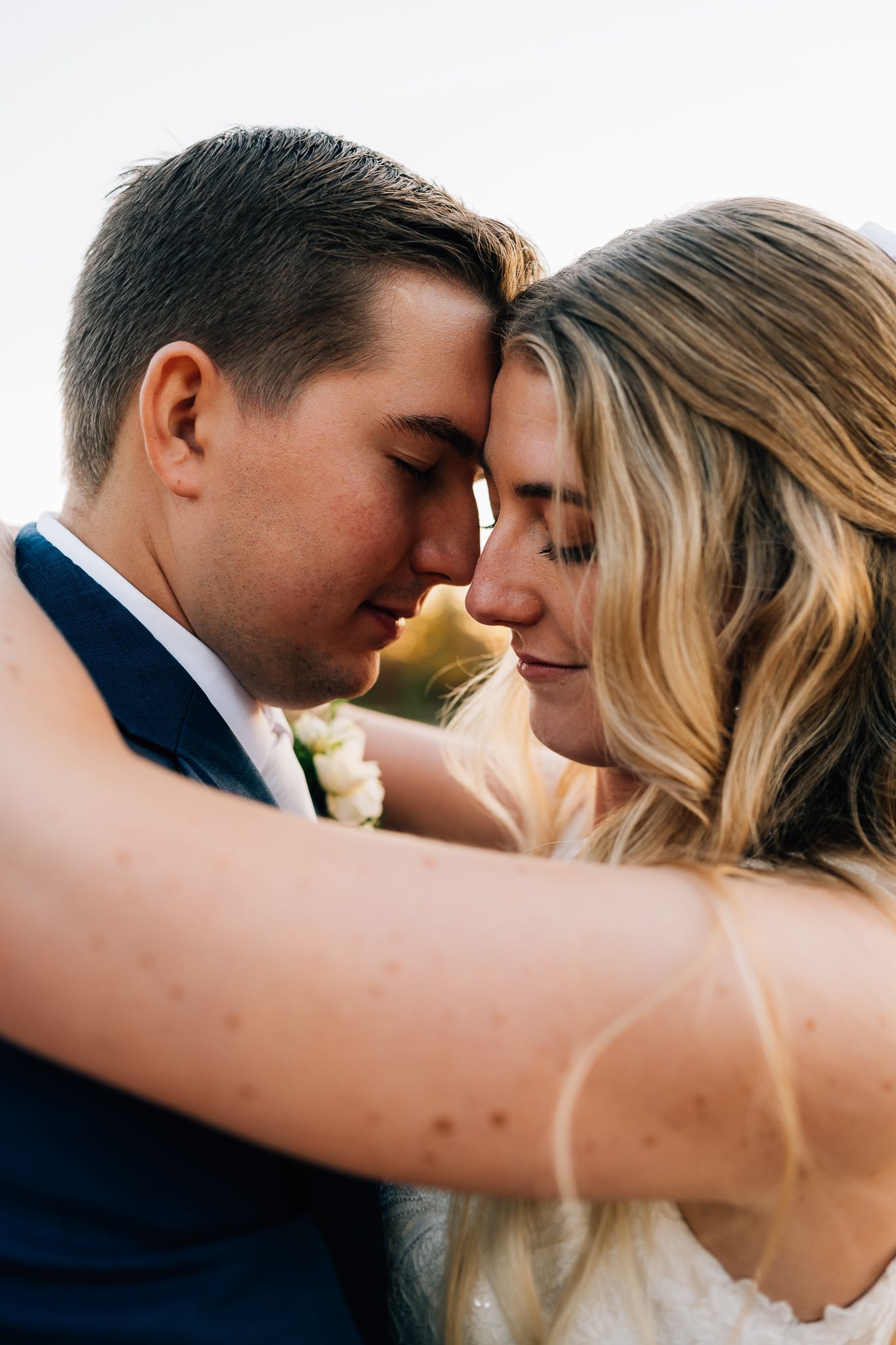 An intimate close-up of a couple sharing a tender moment in wedding attire.
